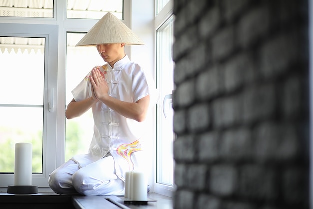 Garçon asiatique en kimono lisant un vieux livre assis près de la fenêtre