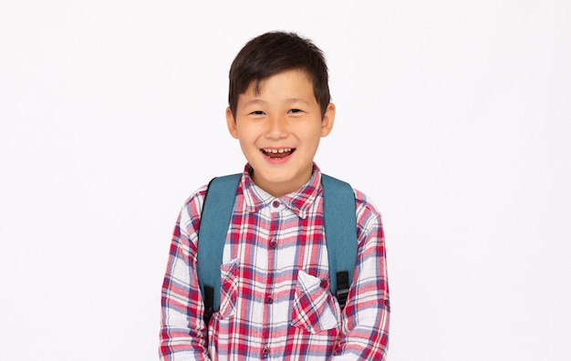 Garçon asiatique mignon de portrait d'enfant allant à l'école avec le petit sac d'école, d'isolement au-dessus de la surface blanche