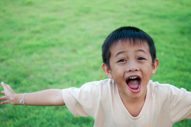 Garçon asiatique mignon rire joyeusement sur le vert de l&#39;herbe.