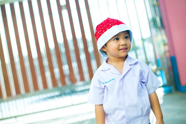 Garçon asiatique portant l'unifrom scolaire et le bonnet de Noel
