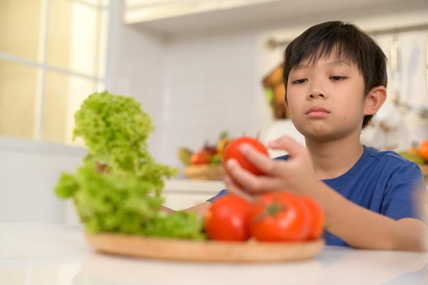 Garçon asiatique s'ennuyant mécontent de manger des légumes concept de soins de santé