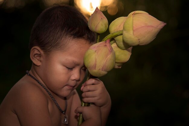 Garçon asiatique tenant une fleur de lotus