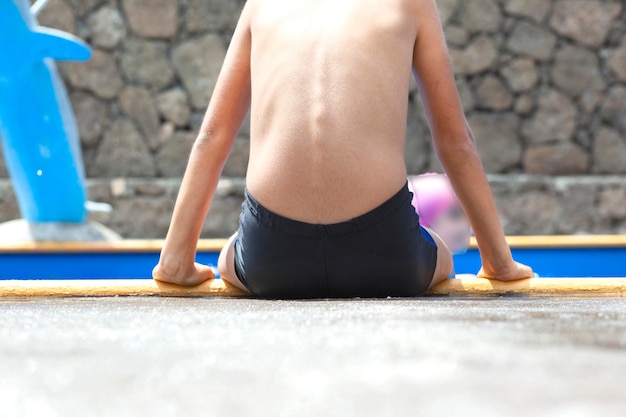 Garçon assis au bord de la piscine