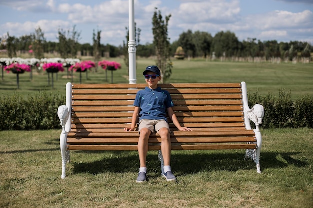 Garçon assis sur un banc dans le parc