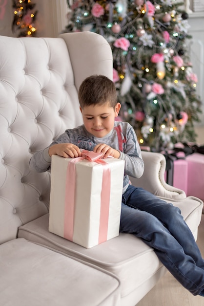Garçon assis sur le canapé et essayant de déballer son cadeau