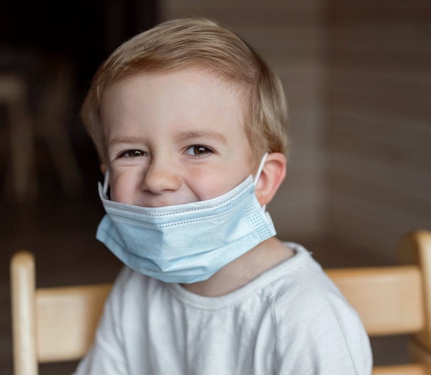 un garçon assis dans un masque médical