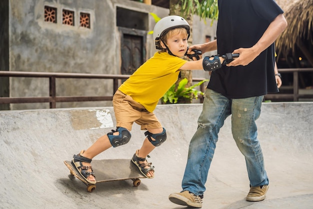 Un garçon athlétique apprend à faire du skateboard avec un entraîneur dans un skate park Sports d'éducation pour enfants