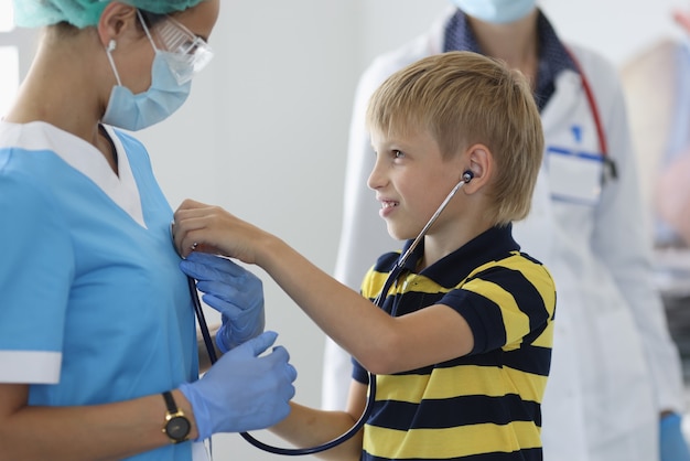 Garçon au cabinet médical écoute le souffle du médecin à travers un stéthoscope