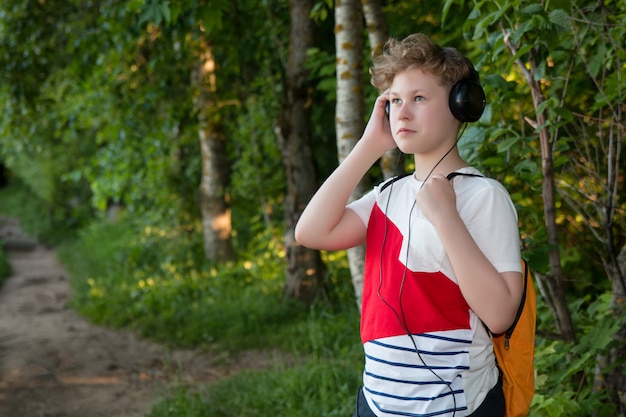 Garçon au casque écoute de la musique. Adolescent au casque dans la forêt