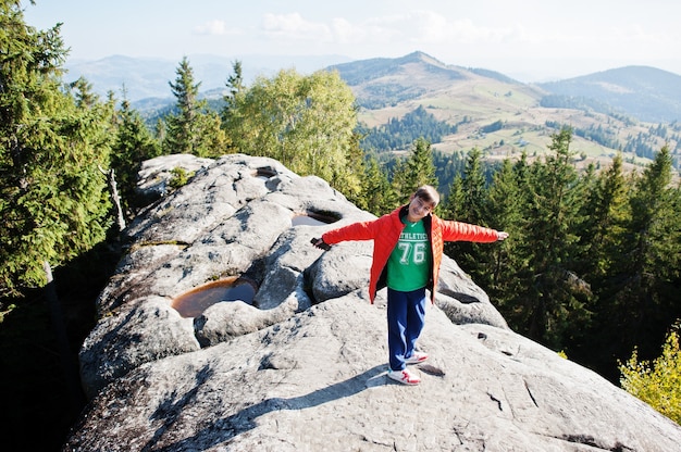 Garçon Au Sommet De La Montagne. Les Enfants Randonnent Par Une Belle Journée Dans Les Montagnes, Se Reposent Sur Le Rocher Et Admirent Des Sommets Avec Une Vue Imprenable. Loisirs Actifs De Vacances En Famille Avec Des Enfants. Activités De Plein Air Et Activités Saines.