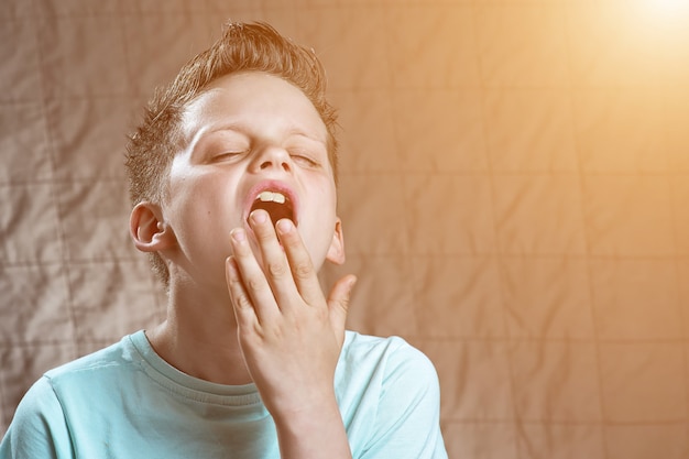 Le garçon au t-shirt est fatigué, veut dormir et bâille