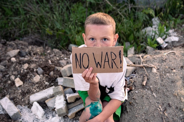 Un garçon au visage crasseux et aux yeux tristes tient une affiche en carton avec l'inscription PAS DE GUERRE