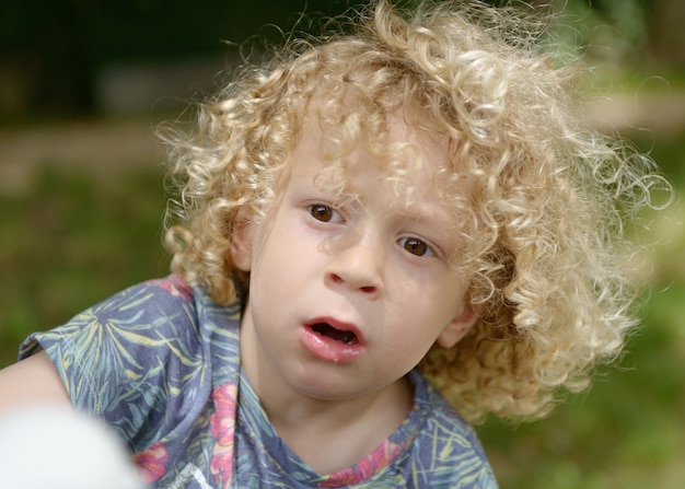 Garçon aux cheveux blonds bouclés, dehors