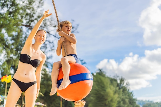 Un garçon sur une balançoire sur la plage Maman et son fils passent du temps sur la plage