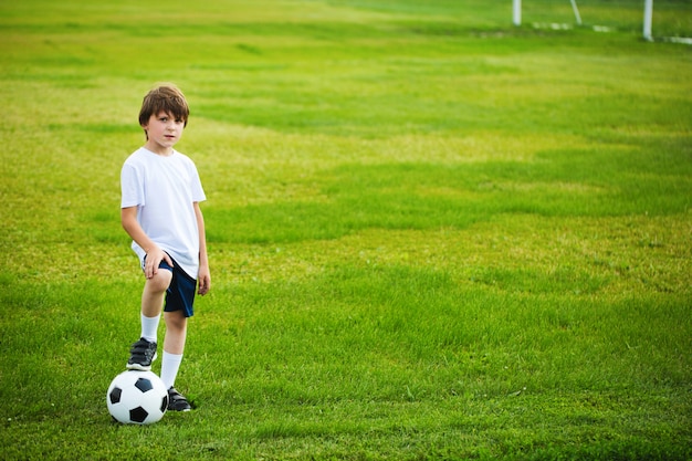 Garçon avec un ballon de football sur le terrain