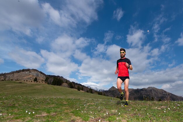 Garçon avec barbe en courant dans une prairie de montagne