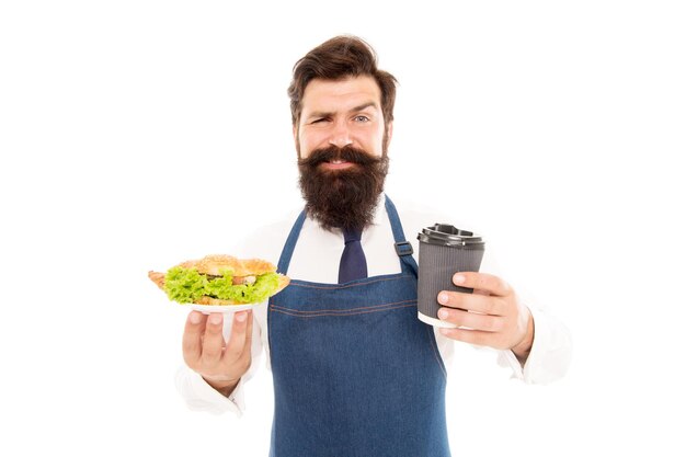 Garçon barbu donnant une assiette avec de la nourriture et une tasse de café. Croissant délicieux. Concept de nourriture de café. Bon appétit. Guy servant de la laitue farcie aux croissants et des légumes frais. Nourriture saine. Repas combiné.