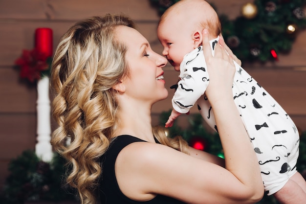 Garçon avec belle maman blonde embrassant dans une maison décorée pour Noël