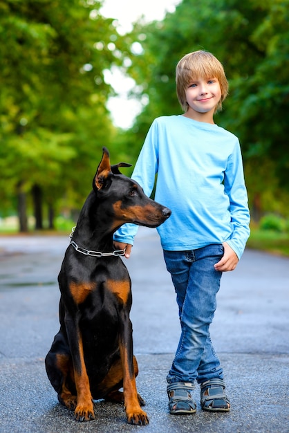 Garçon blond avec doberman dans le parc d'été