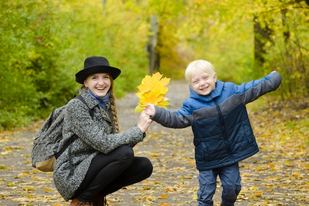 Un garçon blond donne à sa mère un bouquet de feuilles jaunes Forêt d'automne