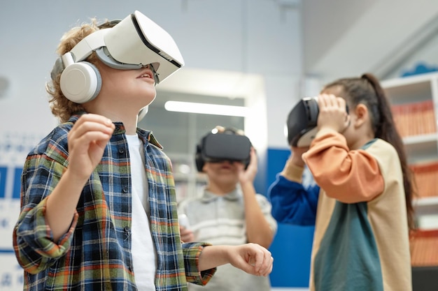 Un garçon blond excité portant un casque VR à l'école