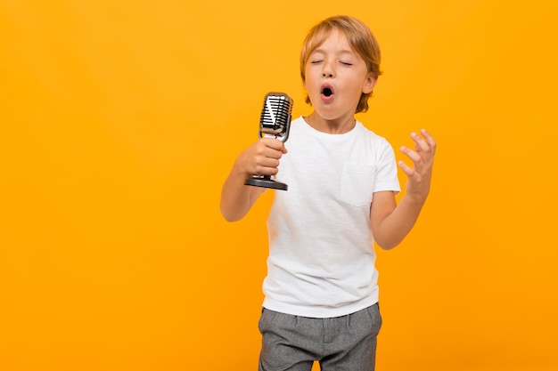 Garçon blond avec un microphone sur fond orange