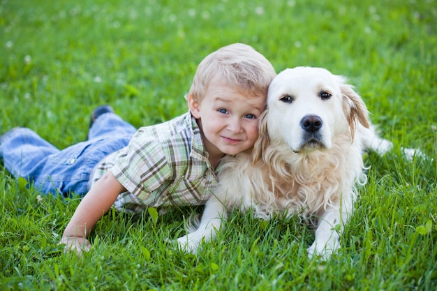 Garçon blond mignon enfant en bas âge avec golden retriever étreignant