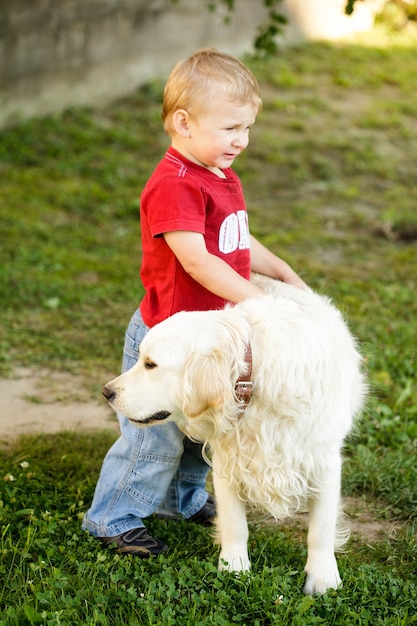 Garçon blond mignon enfant en bas âge avec golden retriever en plein air