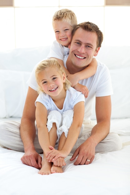 Garçon blond mignon étreignant son père assis sur un lit