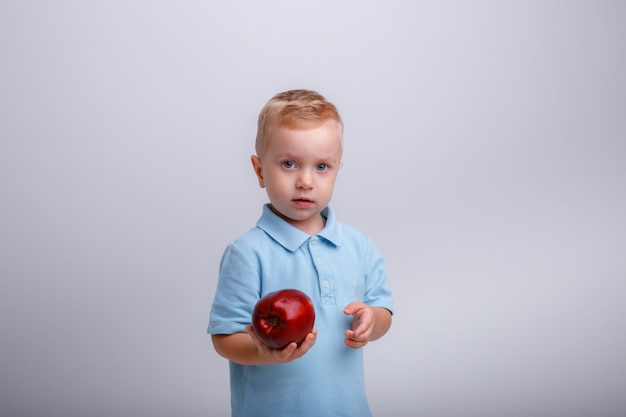 Garçon blond avec une pomme dans ses mains