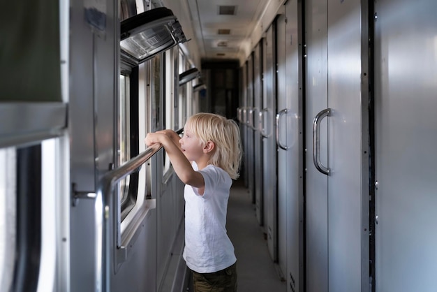 Un garçon blond regarde curieusement la fenêtre du train Voyager avec des enfants