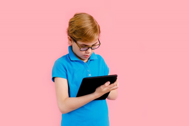 Garçon blond en t-shirt tenant une tablette