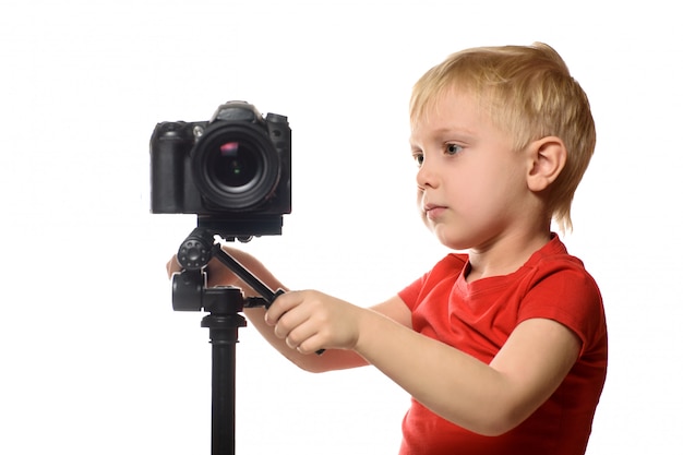 Un garçon blond tourne une vidéo sur un appareil photo reflex numérique.