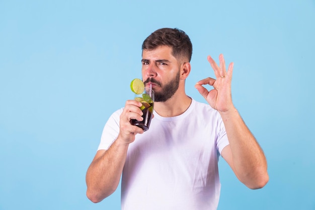 Garçon buvant un soda au cola faisant signe ok