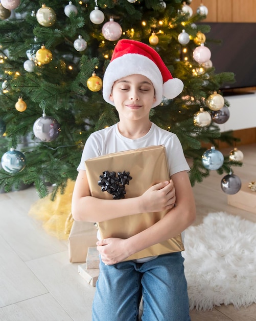 Garçon avec des cadeaux joue près de l'arbre de Noël