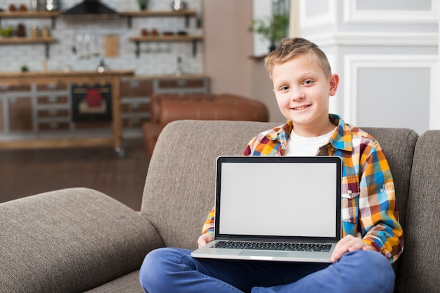 Garçon sur un canapé montrant un écran d&#39;ordinateur portable