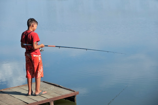 Le garçon avec une canne à pêche. Pêche sur un lac par un été ensoleillé