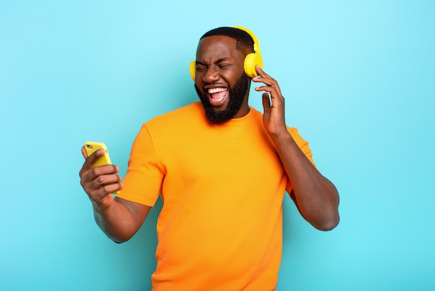 Garçon avec un casque jaune écoute de la musique et des danses. expression émotionnelle et énergétique