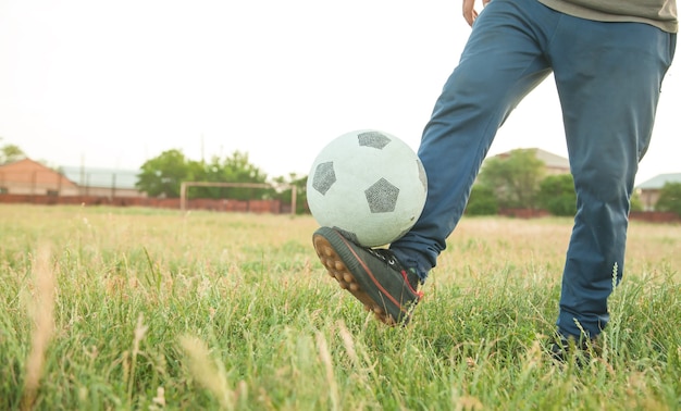 Garçon caucasien avec un ballon de football sur un terrain de football.