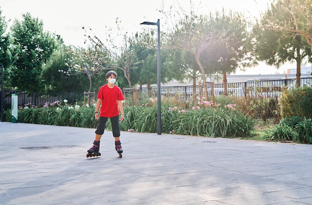 Garçon caucasien avec masque jouant avec des patins à roulettes dans le parc.