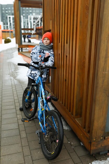 Un garçon caucasien vêtu d'une veste d'hiver se promène à vélo dans la ville