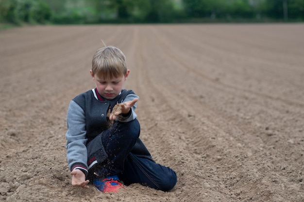 Garçon sur un champ labouré au printemps