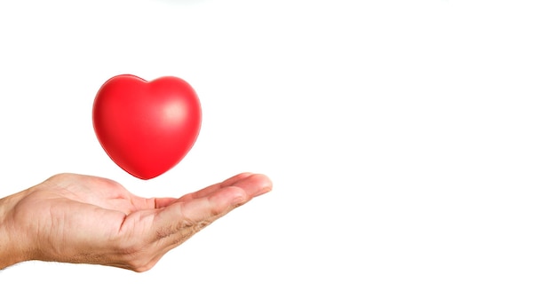 Garçon en chemise bleue avec les mains tendues sous un coeur rouge sur fond blanc, pur