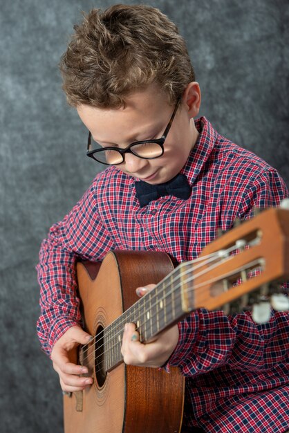 Garçon avec chemise à carreaux jouant sur la guitare acoustique