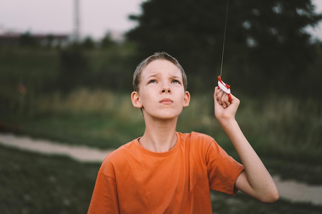 Un garçon en chemise orange regarde un cerf-volant