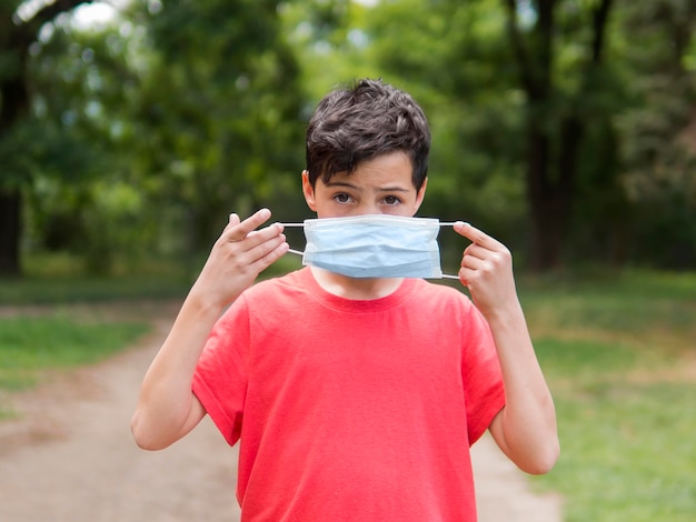 Garçon en chemise rouge portant un masque médical