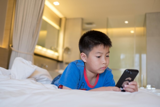 Garçon chinois asiatique jouant au smartphone, enfant utilise un téléphone et joue à un jeu, un jeu accro et un dessin animé