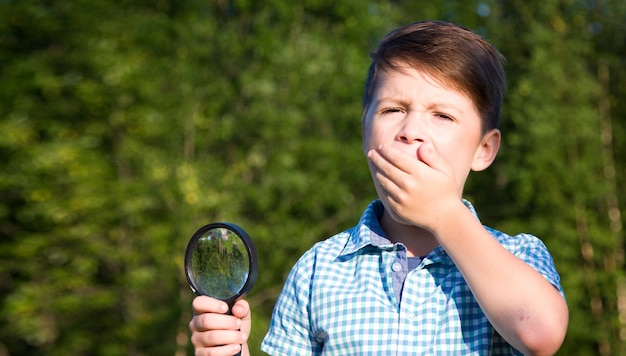 Garçon choqué avec une loupe en été