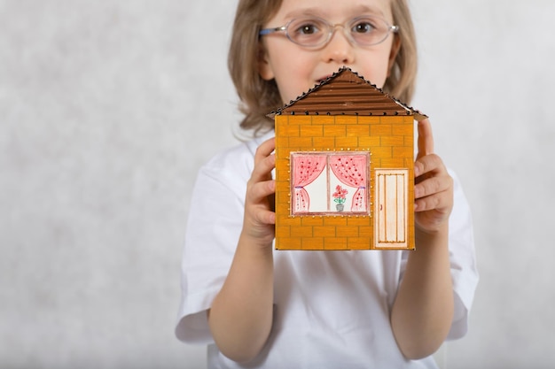 Un garçon de cinq ans garde une maison en papier carton faite à la main. Fermer