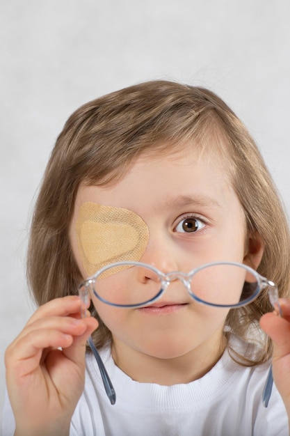 Garçon de cinq ans avec un œil couvert par un coussinet pour les yeux et avec des lunettes.